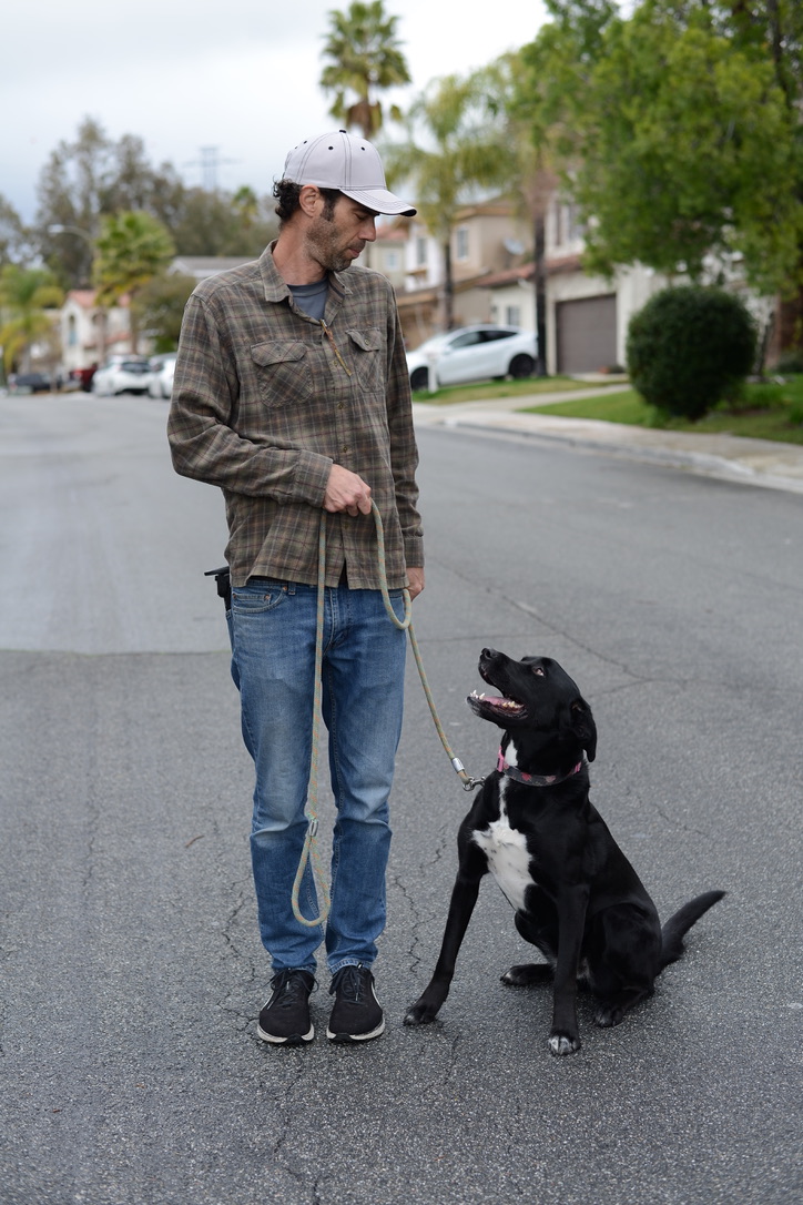 Raam standing beside a seated dog during a private neighborhood training session